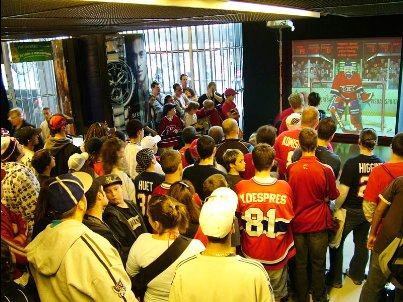large crowd watching person play hockey on a full swing sports simulator
