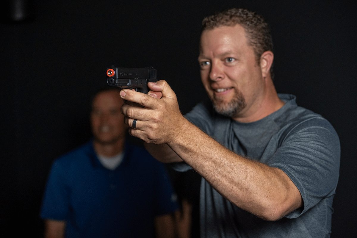close up of man holding laser shot gaming pistol