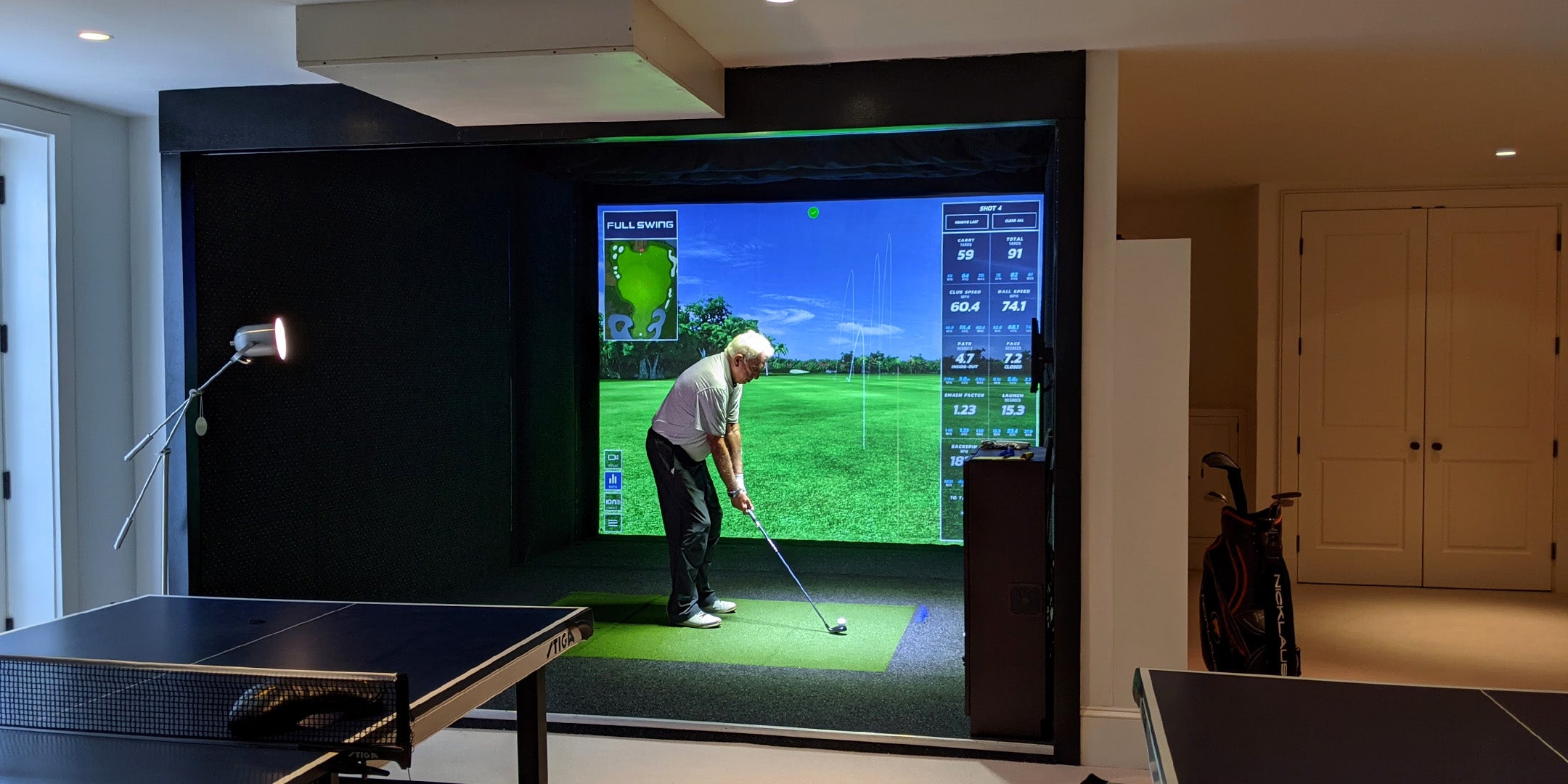 man playing golf simulator in basement of home